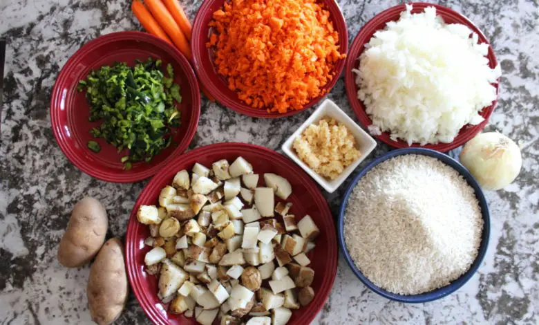 Minced carrots, poblano pepper,garlic,white onion.potato on plates next to uncooked rice